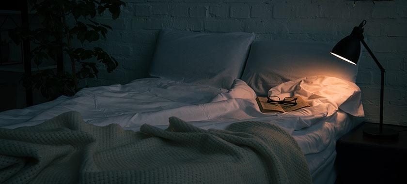 夜のベッドと読書灯が灯る静かな部屋の風景
