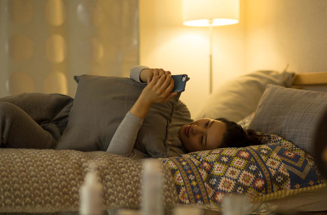 ベッドでスマホを見ながらくつろぐ女性の夜の時間